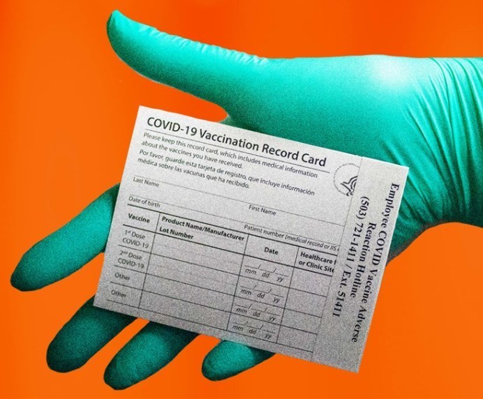 gloved hand holding COVID-19 Vaccination Record Card